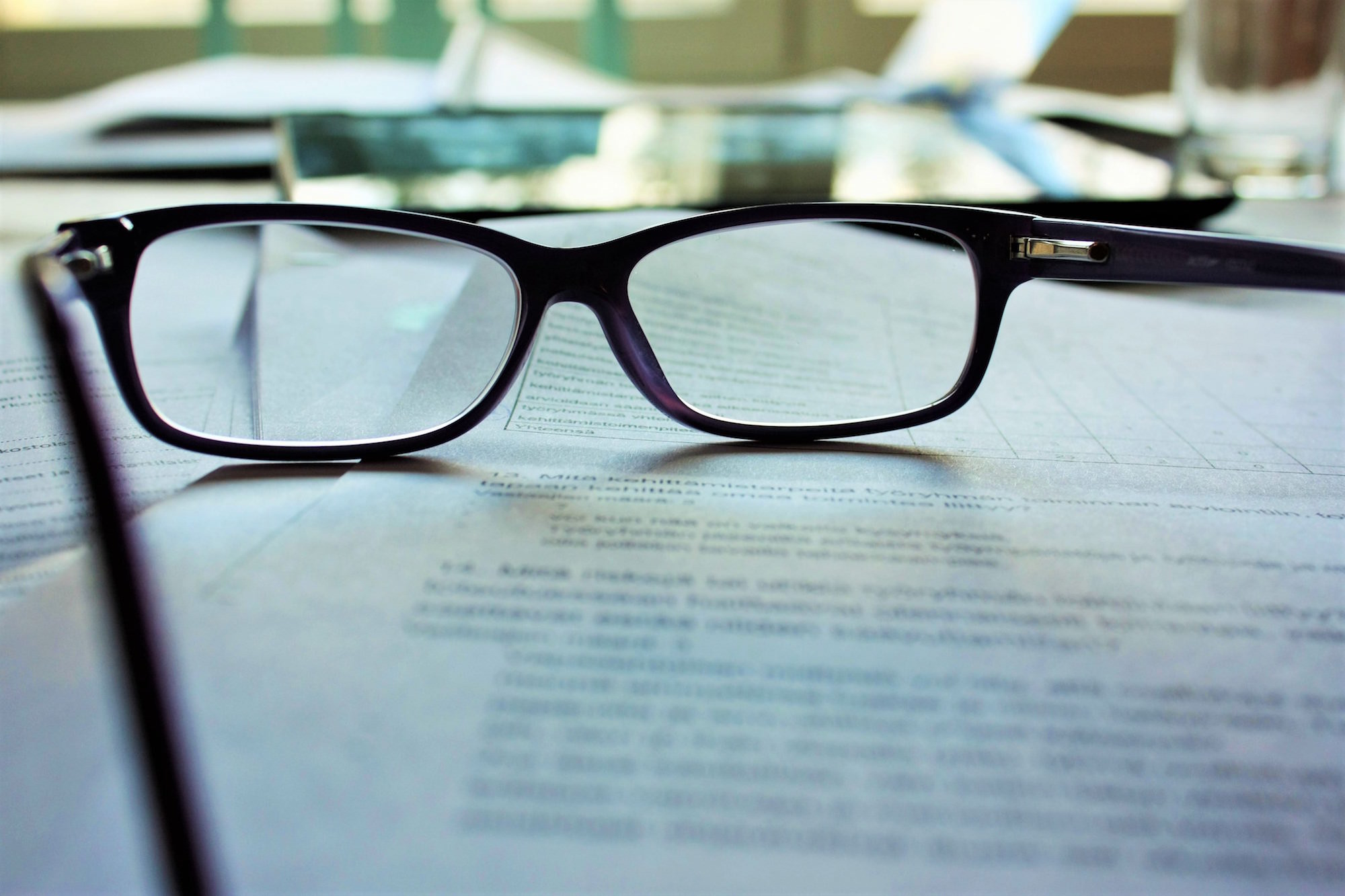 A pair of glasses sitting on top of a blurry document.