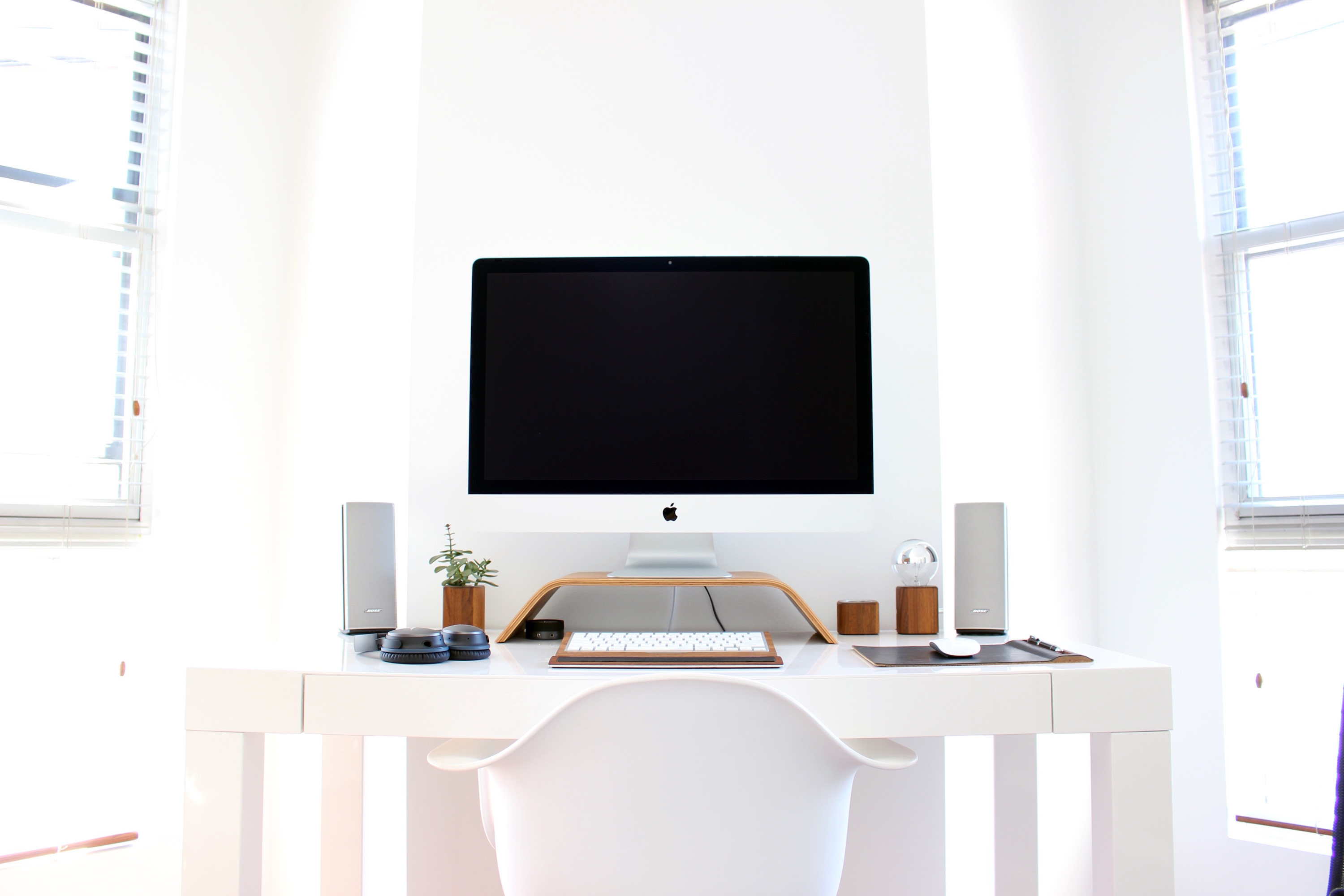 A very bright, modern, minimalistic office with an iMac computer sitting on a desk.